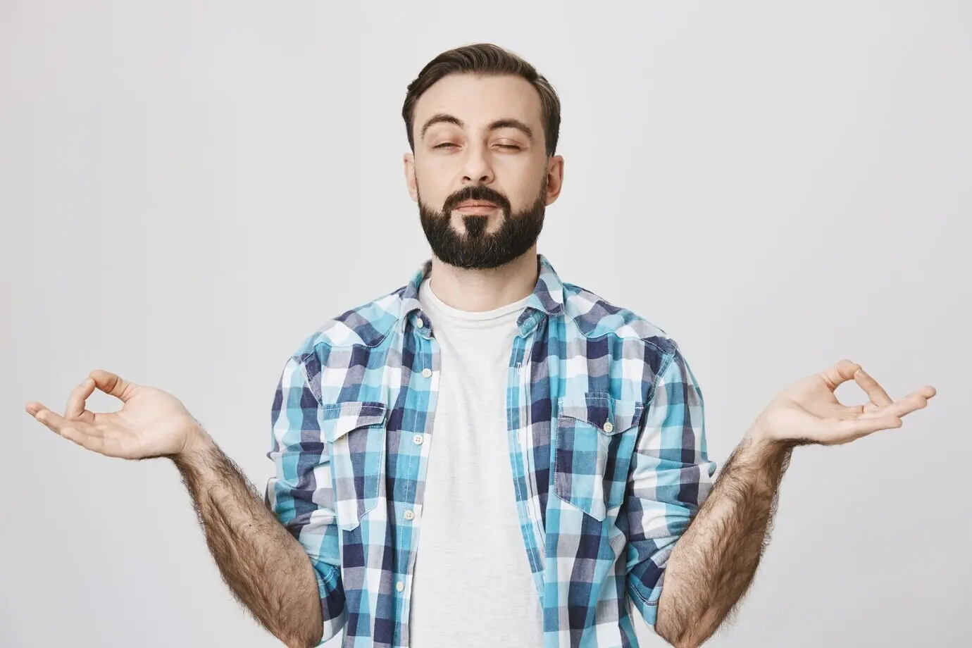 Расслабленный бородатый парень медитирует, занимается йогой.